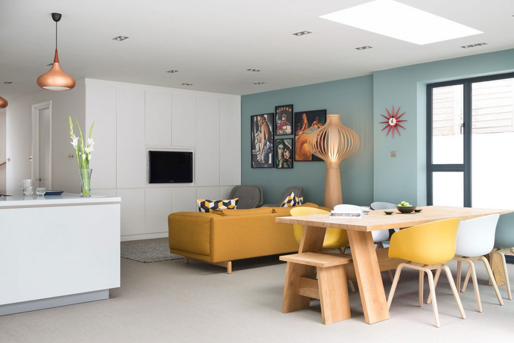 yellow and white seating in a kitchen with blue walls and a spiky red clock to illustrate a feature on kitchen must-haves for entertaining 