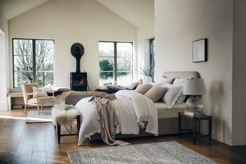 Scandi bedroom with neutral bedding, faux fur and log burner