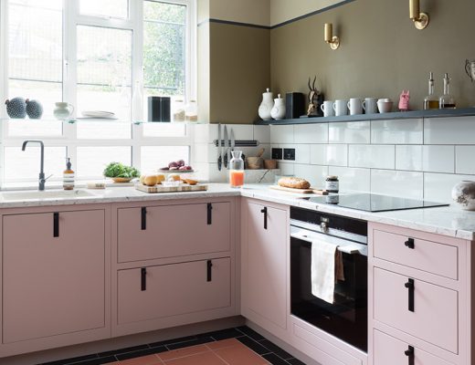 a small kitchen with pale pink and black cabinetry