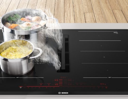 a hob with extractor in a kitchen with two stainless steel pans containing food steaming on top of it