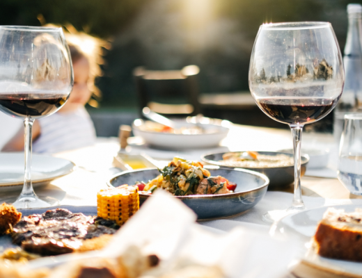 a dining table featuring wine glasses and lots of food fresh from the barbecue