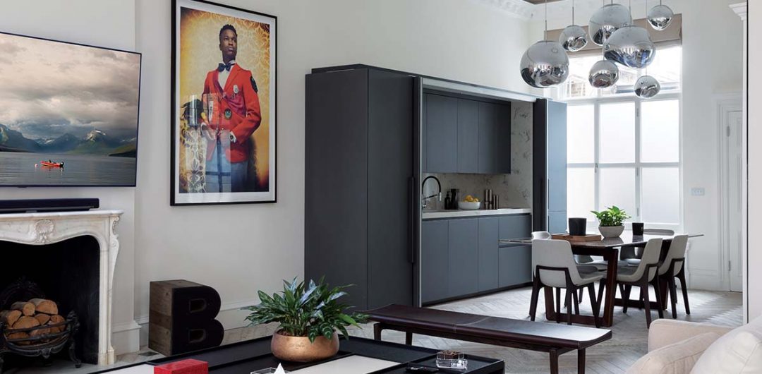 a hidden kitchen featuring matt black bespoke cabinetry
