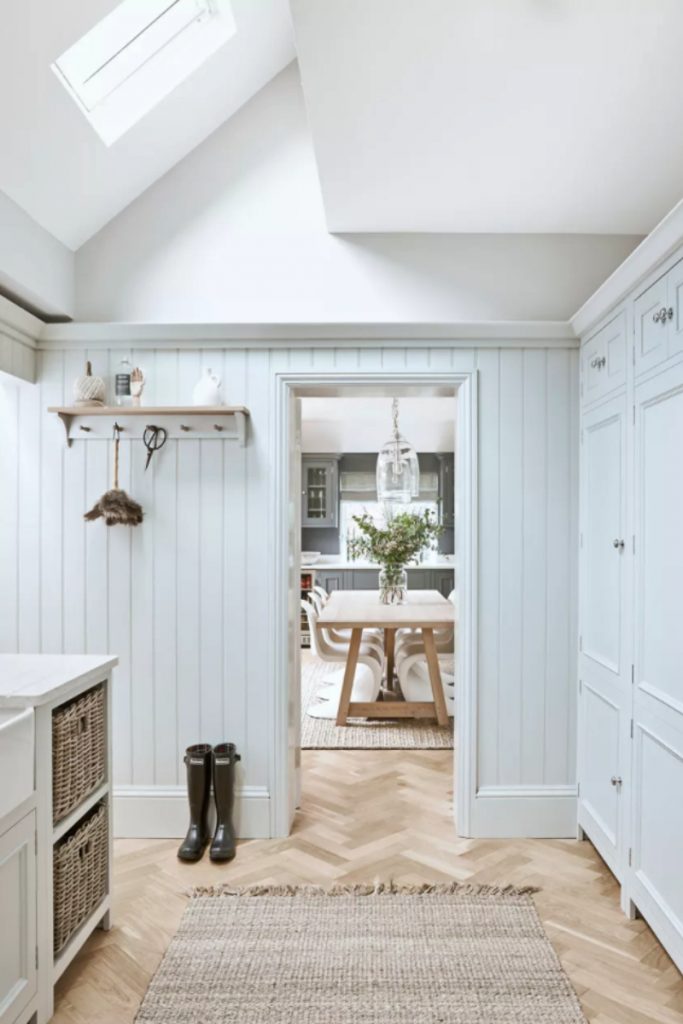 a utility room painted in pastel blue with open shelving and a dining table and chairs visible through the doorway