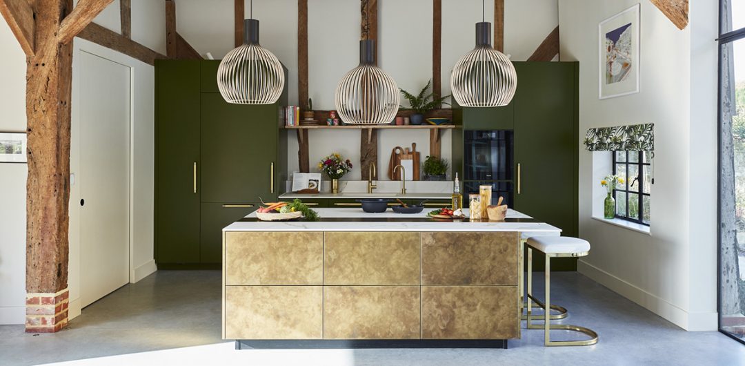 a Sola Kitchens design featuring a white and brass kitchen island with three pendant lights above it