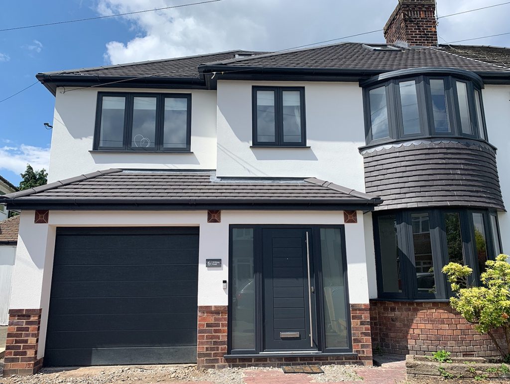 the front of a large semi-detached house with brown framed windows and a modern black front door