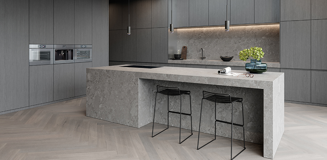 a grey kitchen with dark grey handleless cabinetry and a stone kitchen island with black bar stools