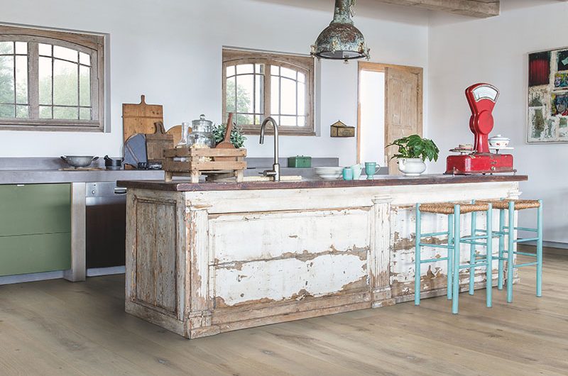 an industrial-style kitchen with a long wooden island with bar stools and wooden beams above them, to illustrate the question of how much a kitchen costs