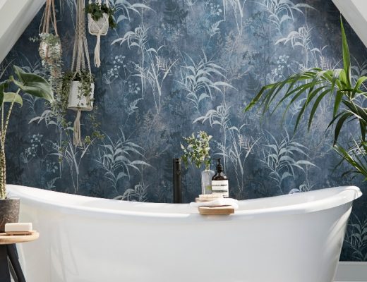 floral blue wallpaper in a bathroom above a white freestanding bath